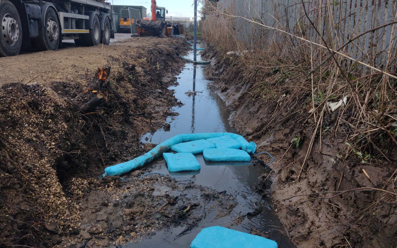 The drainage ditch on site during CTSL Spill Specialists' kerosene spill clean up. A vacuum tanker removes contaminated material from the ditch, while absorbent pads soak up excess.