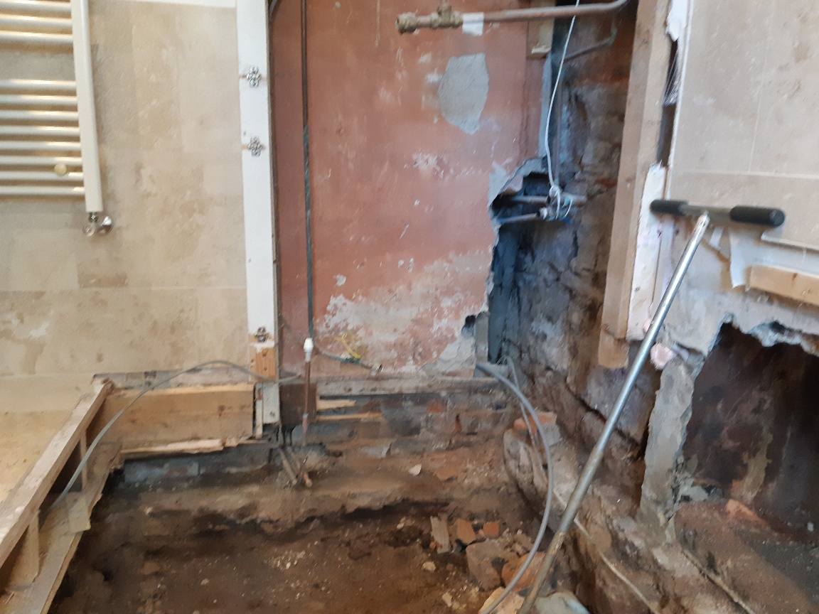 Works underway in the policyholders bathroom following removal of the bath, wall finishings, cylinder and tank, showing the floor dug out and contaminated building material removed.